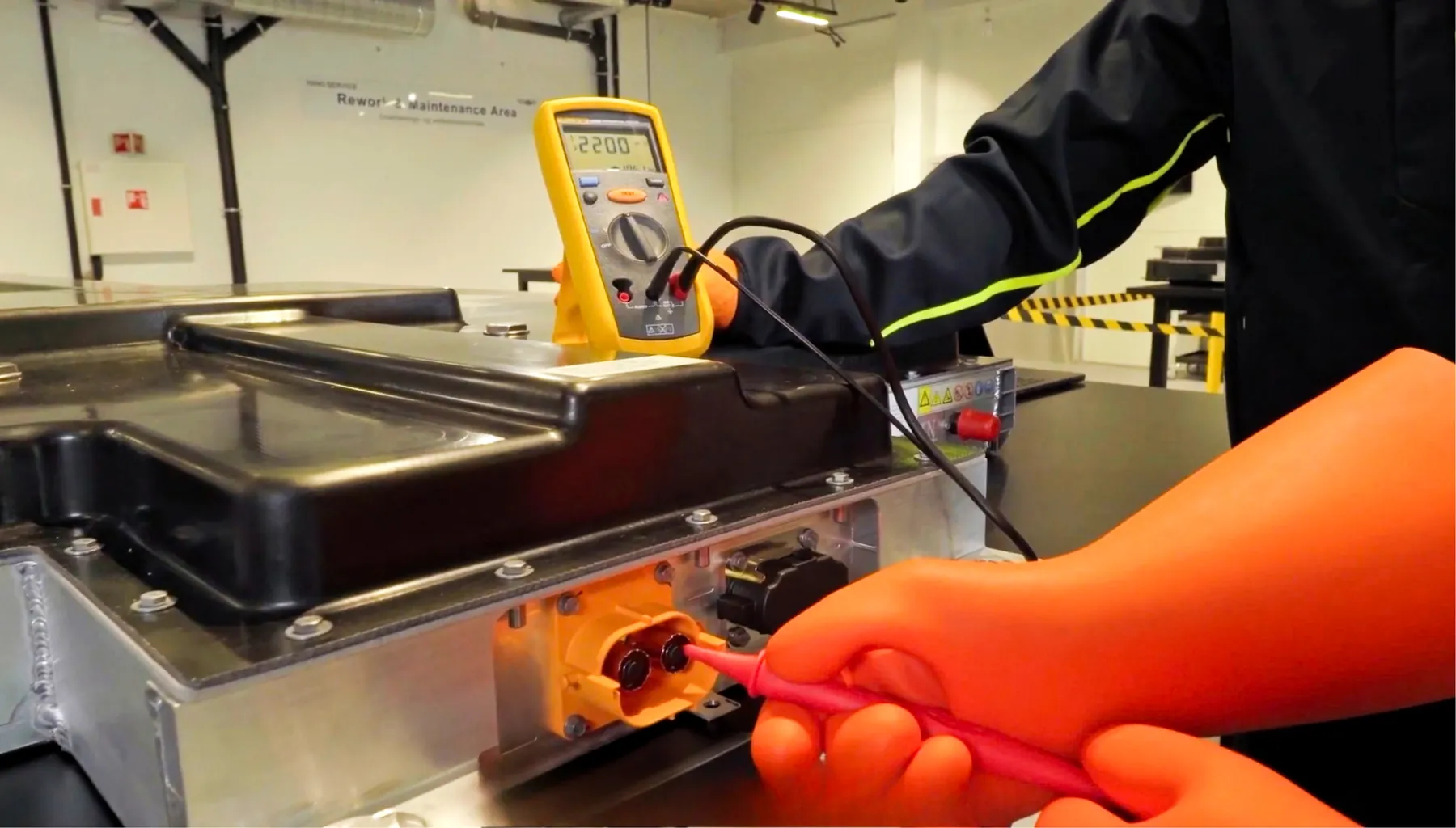 A YES-EU technician measuring a battery component with a multimeter
